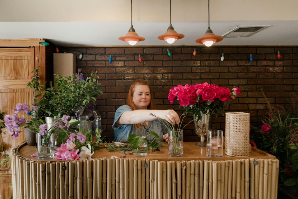 A female florist arranging a vibrant bouquet in an indoor floral shop setting.